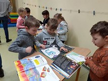 Dzieci oglądają ksiązki o dinozaurach.