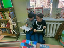 chłopcy siedzą na krześle i czytają książkę.