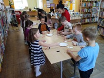 Dzieci pracuja przy stolikach, robią bociana z wacików kosmetycznych.