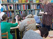 Uczestnicy siedzą przy stolikach podczas tworzenia pracy plastycznej