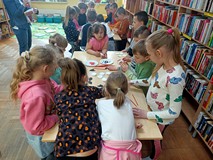 Dzieci pracuja przy stolikach, robią bociana z wacików kosmetycznych.