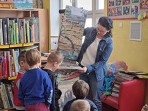 Bibliotekarka prezentuje dzieciom książkę.