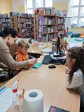 Bibliotekarka pokazuje dziecku jak wypożyczmy książki.
