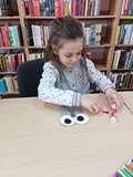 Dziewczynka wykonuje sowę z papieru.