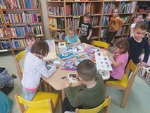 Dzieci w czytelni przeglądają książeczki, grają w gry i układają puzzle