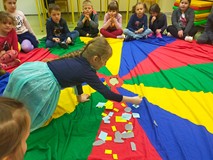 dzieci siedzą na chuście animacyjnej i opowiadają o symbolach wielkanocnych