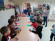 Dzieci stoją przy stołach i wykonują zajkładki