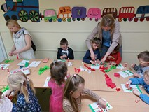 Dzieci wykonują pracę plastyczną przy stolikach