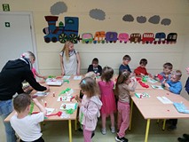 Dzieci wykonują pracę plastyczną przy stolikach