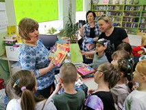 Bibliotekarka rozdaje dzieciom książki-upominki