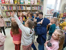 Dzieci podczas zajęć, stoją i pokazują ukrytą kopertę