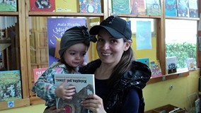 Mama z córeczką pozują do zdjęcia z książką