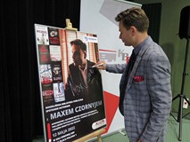 Max Czornyj podpisuje plakat wydarzenia.