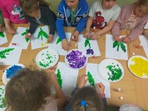 Dzieci podczas zajęć plastycznych, siędzą przy stole i przyklejają kolorewe karteczki