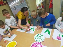 Dzieci podczas zajęć plastycznych, siędzą przy stole i przyklejają kolorewe karteczki