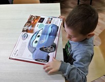 Chłopiec ogląda książkę o samochodach