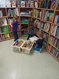 Dzieci w czytelni przeglądają książeczki