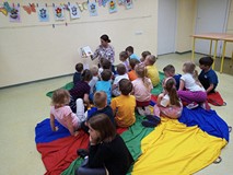 Dzieci słuchają bajki czytanej przez bibliotekarkę