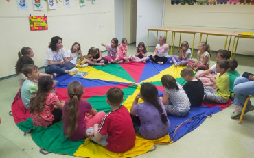 Dzieci podczas zajęć siedzą na kolorowej chuście i dyskutują na temat ochrony środowiska