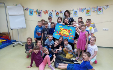 Dzieci z biblotekarką pozują z plakatem przyjaźni.