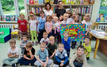 Bibliotekarki i dzieci pozują z plakatem przyjaźni