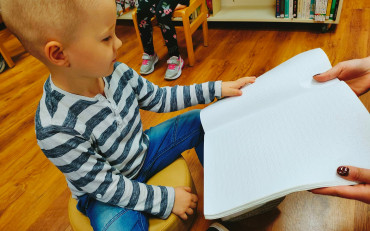 Dziecko dotyka czasopisma napisanego w języku Braila