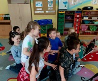 Dzieci zdmuchują kropki w książce pt. 