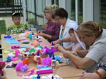 Warsztaty plecenia wianków, uczestniczki wykonują kwiaty z papieru