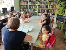 Bibliotekarka czyta dzieciom fragment książki Grzegorza Kasdepke