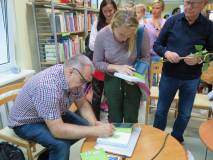Marcin Kostrzyński składa autograf na książce.