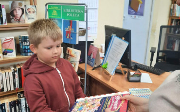 Bibliotekarka wręcza dyplom chłopcu