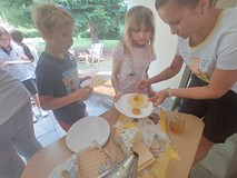 Bibliotekarka nakłada dzieciom miód do degustacji