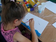 dziewczynka maluje prace plastyczną