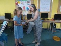 bibliotekarka rozdaje dzieciom nagrody