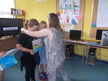 bibliotekarka wiesza na szyi medale nagrodzonych dzieci