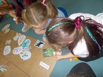 dwie dziewczynki przyklejają na tablicę gatunki zwierząt