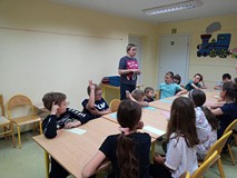 Dzeici siedzą przy stolikach i wykonują pracę plastyczną