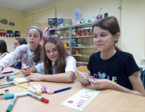 Dzeici siedzą przy stolikach i wykonują pracę plastyczną