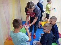 Animatorka rozdaje dzieciom kolorowe kartki