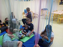 Dzieci siedzą na materacach i słuchają opowiadania