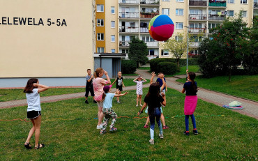 Dzieci grają w zbijaka ogromną, dmuchaną piłką