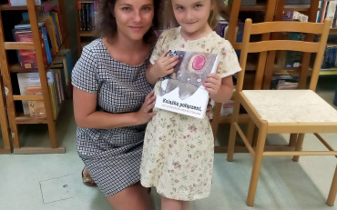 Dziewczynka z bibliotekarką prezentują książeczkę