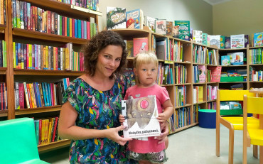 dziewczynka z bibliotekarką prezentują książeczkę