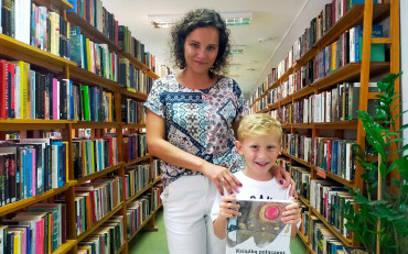 Dziecko z bibliotekarką prezentują książeczkę