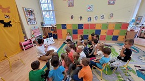 Dzieci słuchają książeczki czytanej przez bibliotekarkę