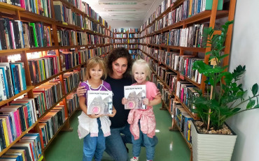 Dziewczynki z bibliotekarką prezentują książeczki