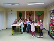 Dzieci stoją przy stołach podczas pracy plastycznej
