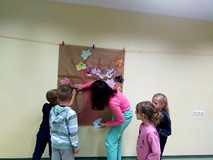 Dzieci wraz z bibliotekarką wspónie wykonują plakat