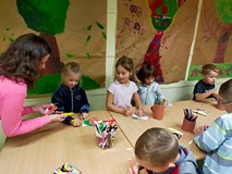 Dzieci stoją przy stołach podczas pracy plastycznej