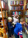 Dzieci stoją między regałami i przeglądają książki